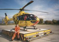 Dr. med. Ralf Kowalzik sitzt vor einem Rettungshelikopter